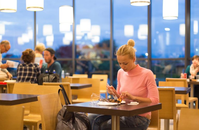 Woman working at a table in an airport waiting area.