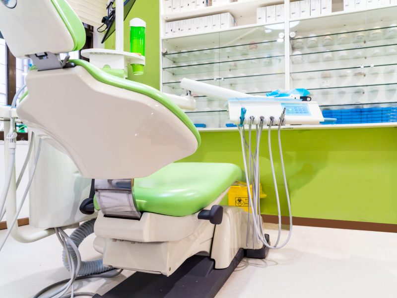 A dentists office with a green chair